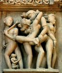 A temple relief at Khajuraho in Madhya Pradesh, India features a couple in a sexual embrace with a man and a woman masturbating to either side.